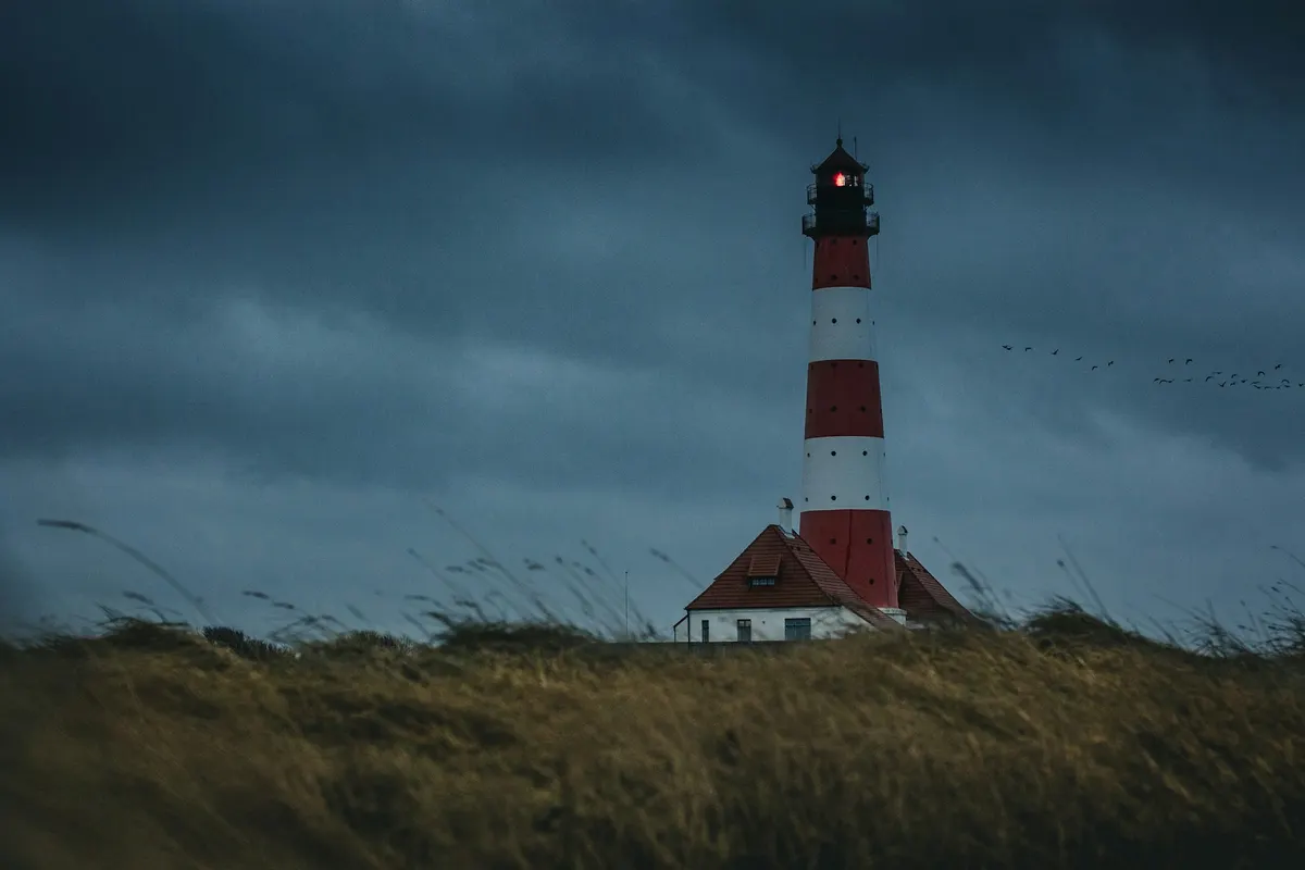 Rot-weißer Leuchtturm unter einem dunklen Sturmhimmel