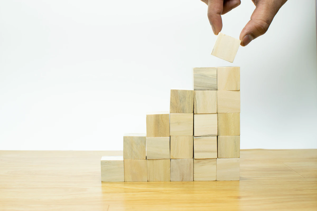 Hand setzt Holzklötze Stufe für Stufe zu einer Treppe zusammen